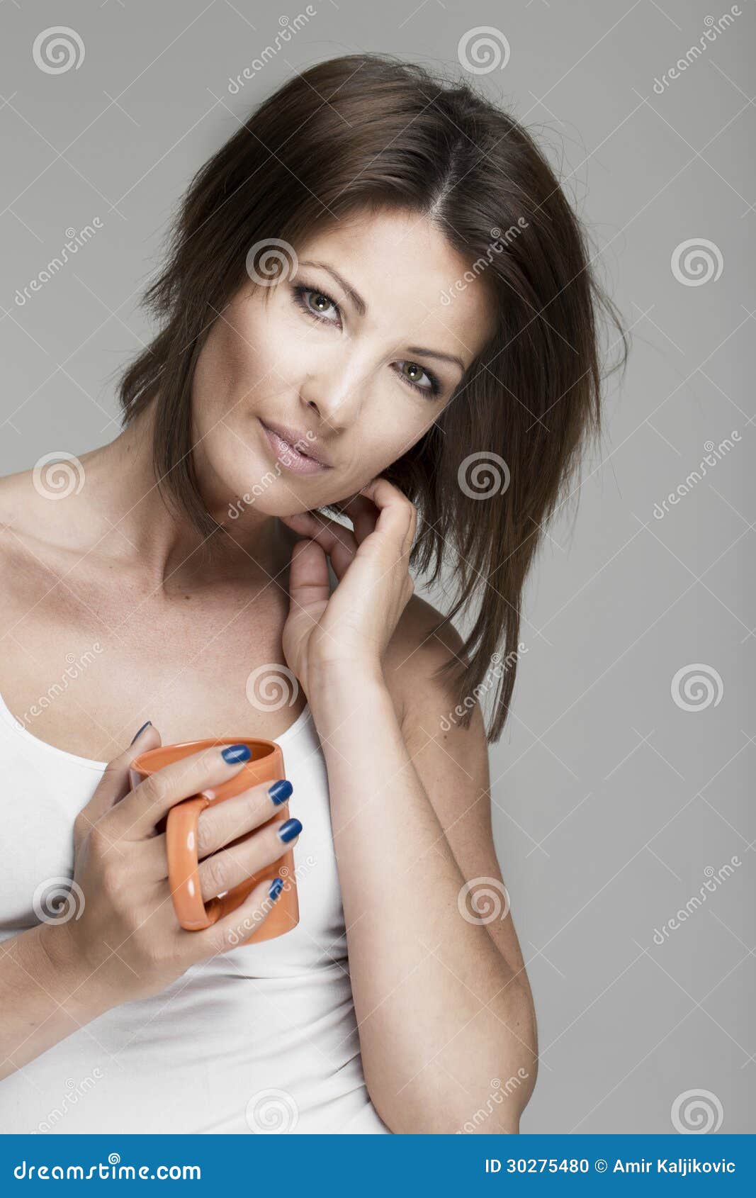 Woman drinking mug of coffee. Attractive thoughtful woman holding mug of coffee contemplating on gray background.