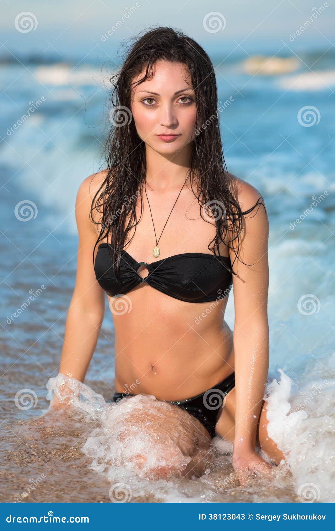 Attractive wet brunette sitting on the beach