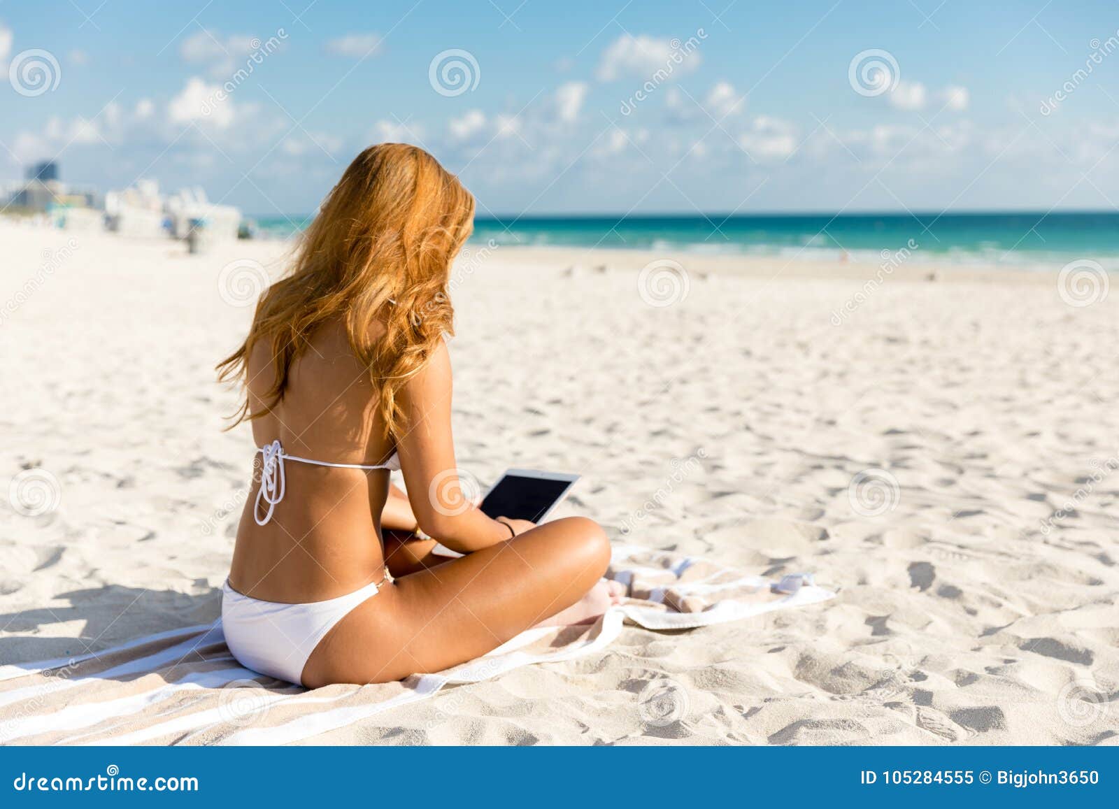 Girl in Bikini Sitting at the Beach Using a Tablet Computer Stock Image