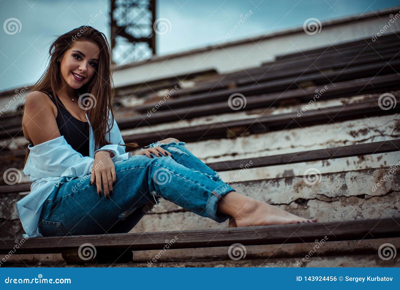 Attractive Woman Sitting With Bare Feet In The Stadium She`s Wearing A