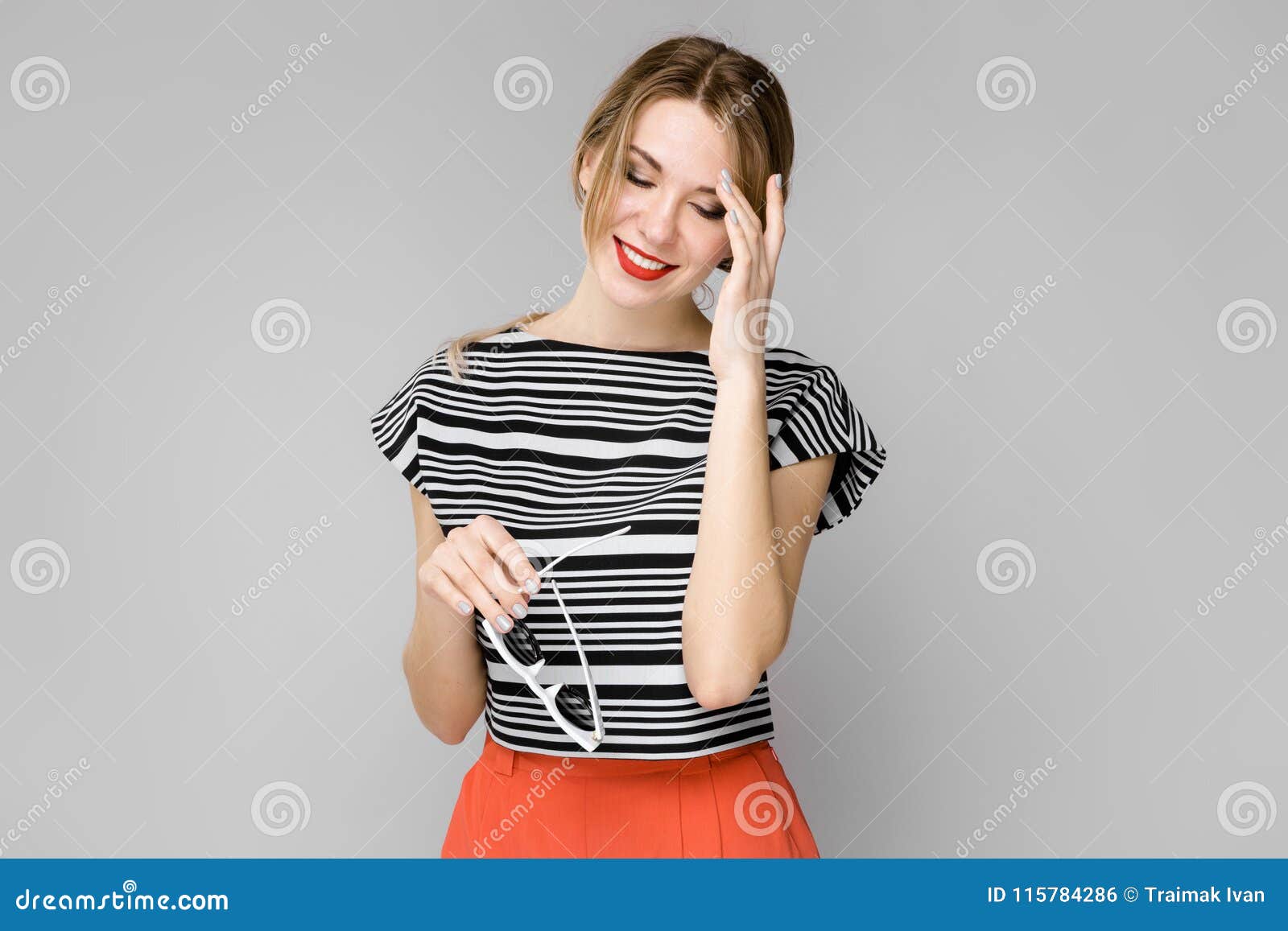 Attractive Young Blonde Shy Girl in Striped Blouse Smiling Holding Her ...