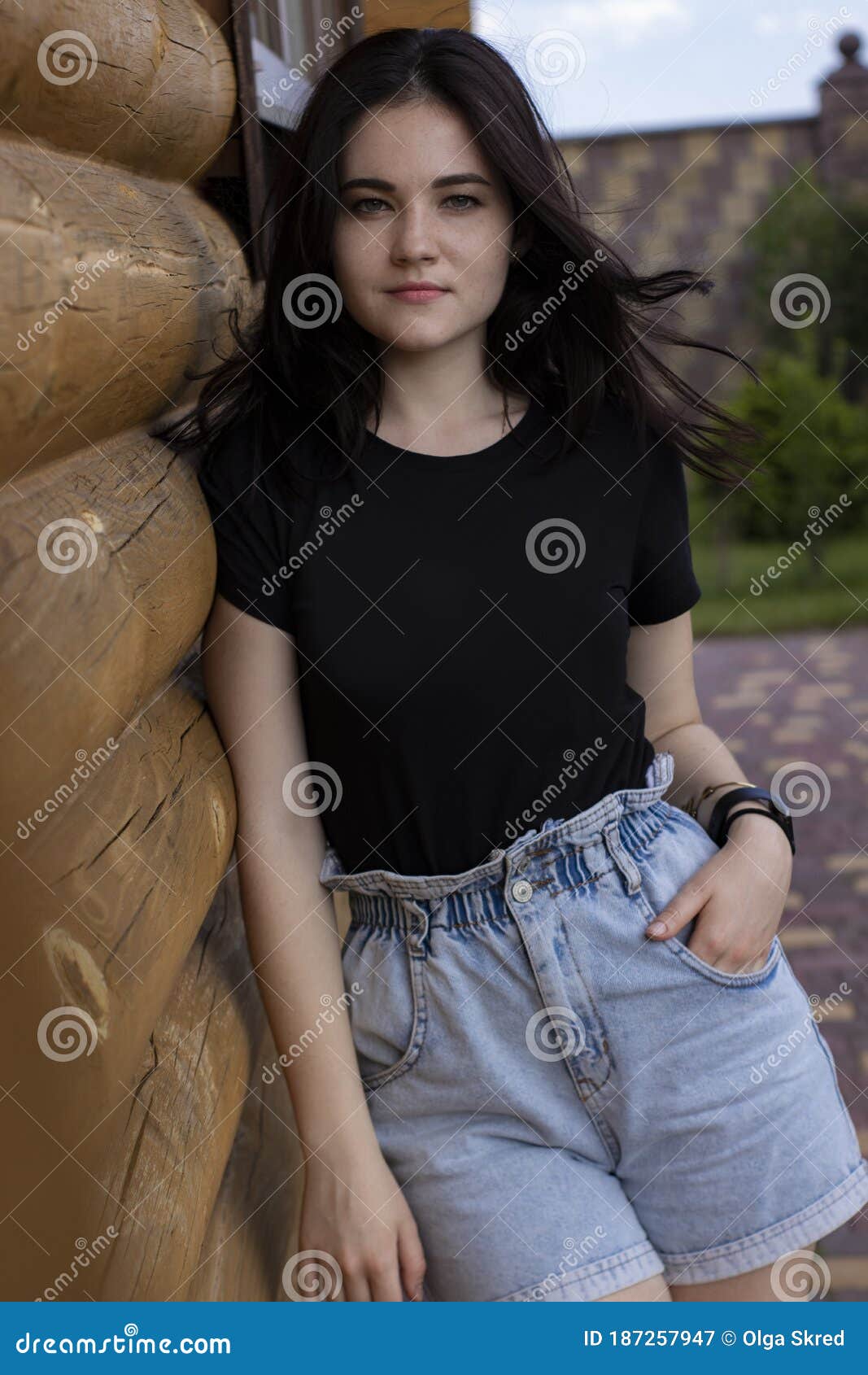 Attractive Young Brunette Woman in Black T-shirt and Denim Shorts Next ...