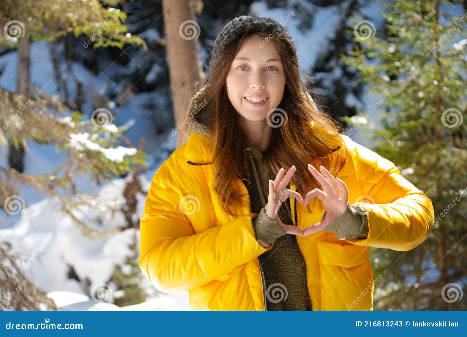 Attractive Young Caucasian Woman in a Down Jacket and Hat Shows a ...