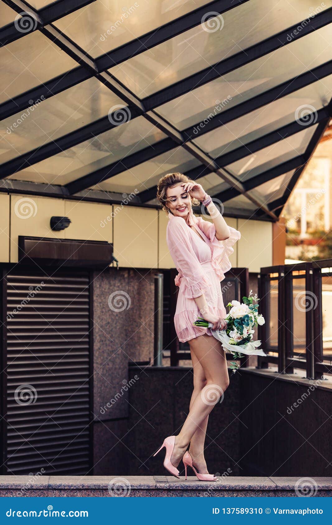 Attractive Young Girl in a Short Dress with a Flower Bouquet Posing on ...