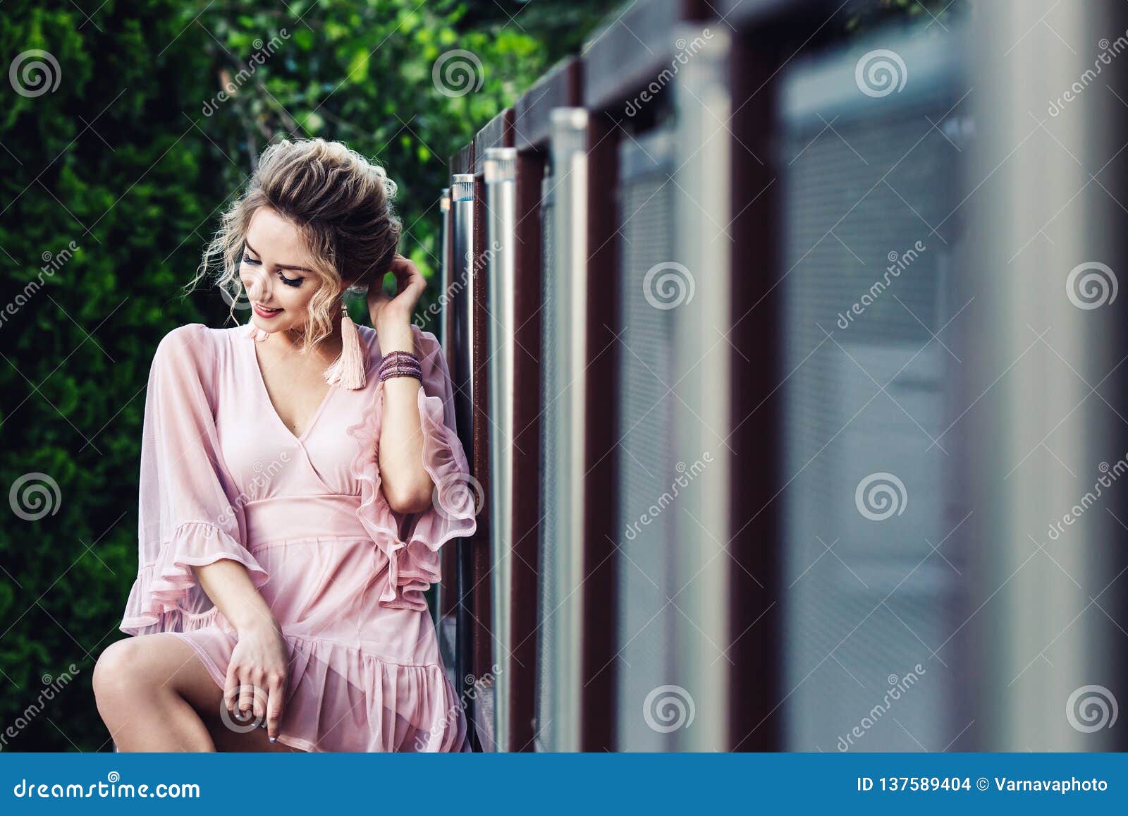 Attractive Young Girl in a Short Pink Dress Posing Near a Steel Fence ...