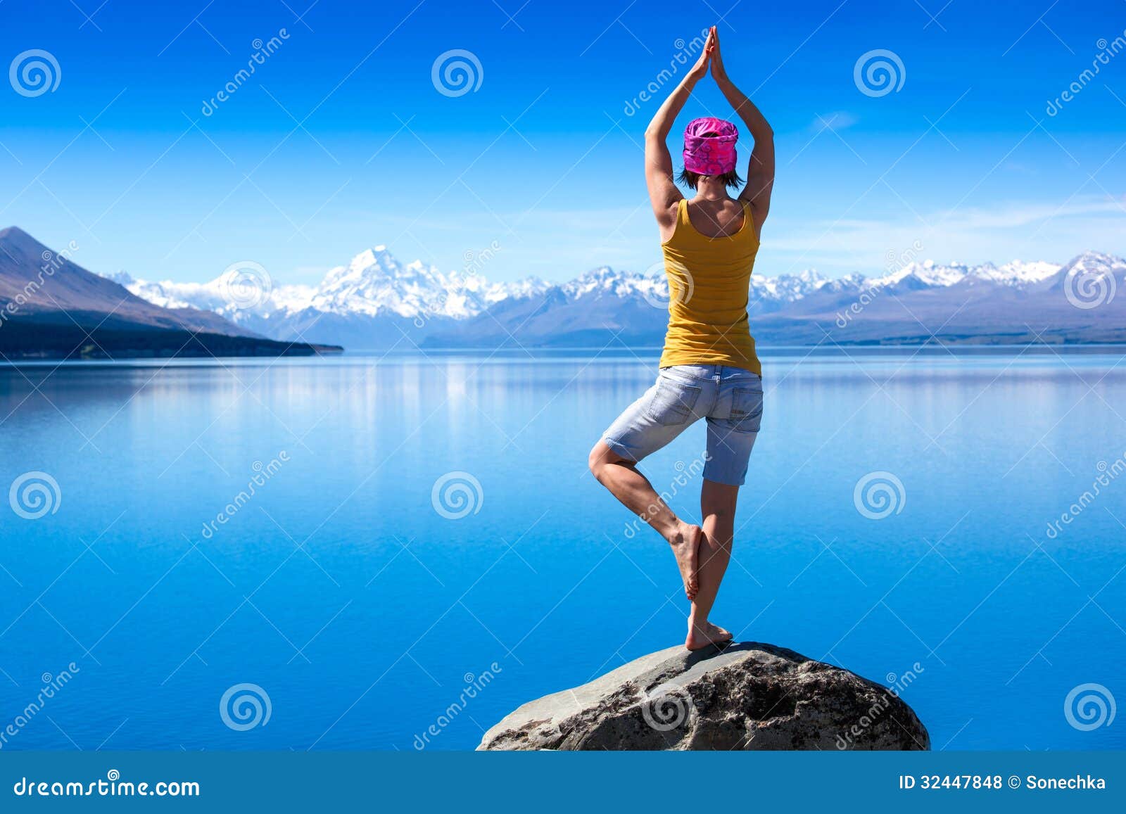 an attractive young woman doing a yoga pose for balance and stretching near the lake