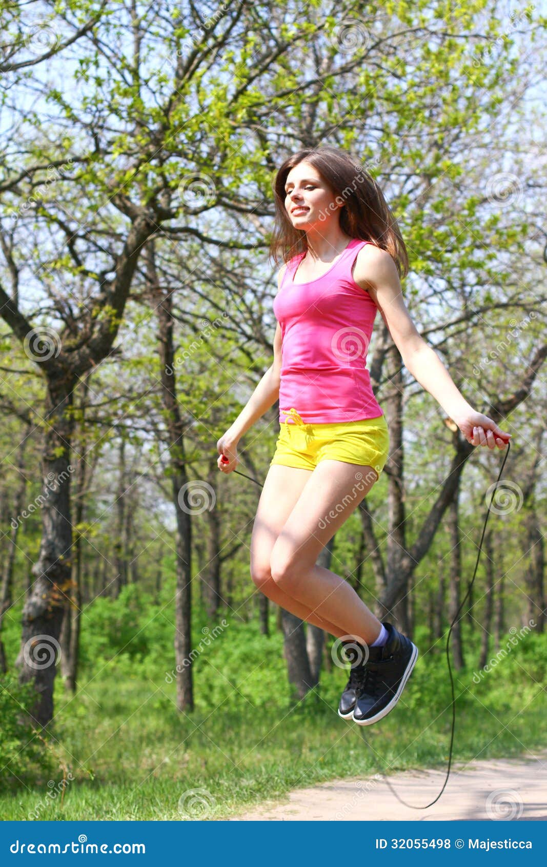 Attractive Young Woman Jumping with a Skipping Rope in a Summer Stock
