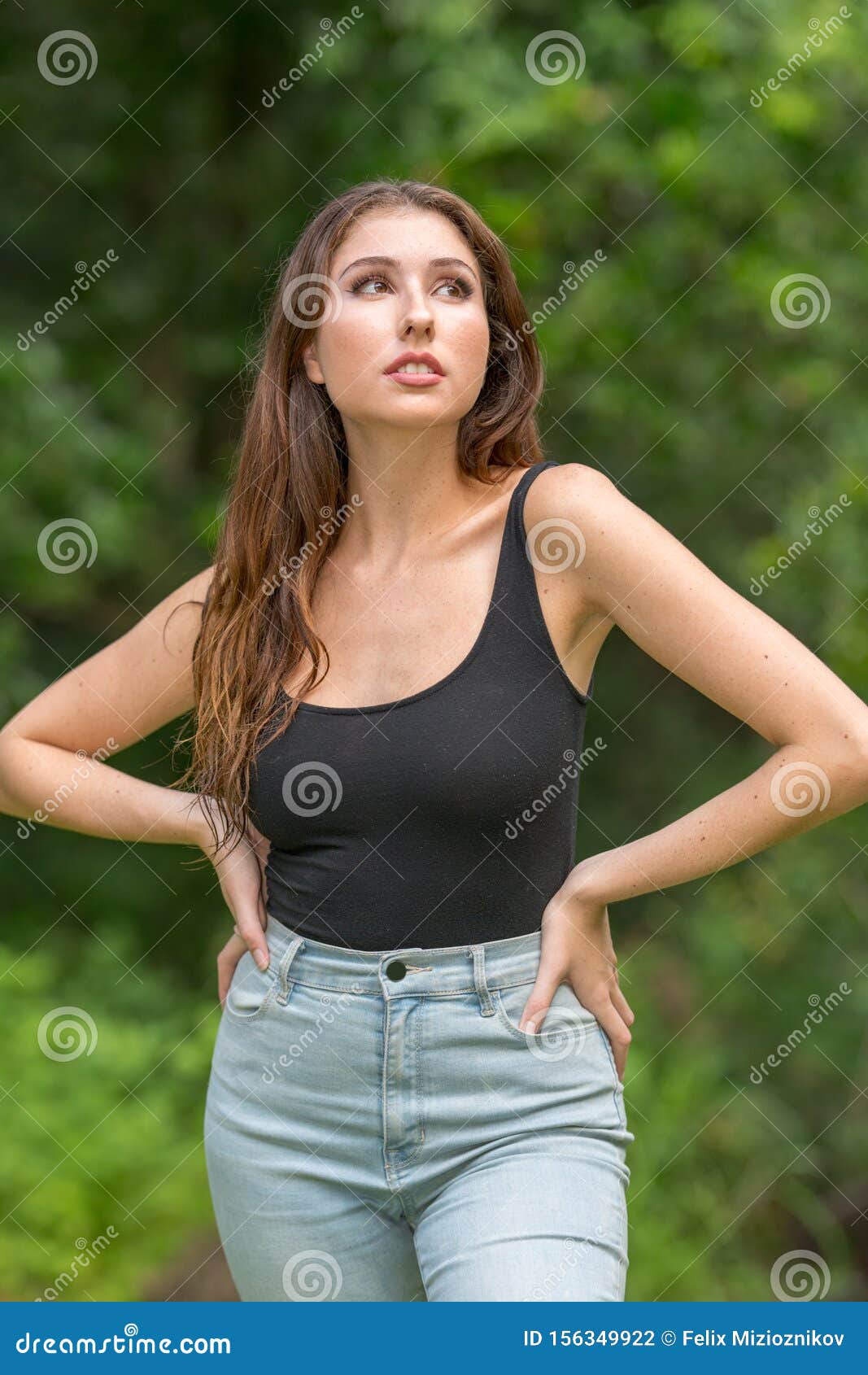 Attractive Young Woman Posing with Hands on Hips and Looking Up Away Stock  Photo - Image of leisure, beautiful: 156349922