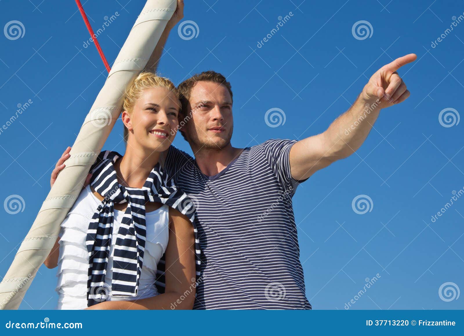 Attraktive Paare auf Segelboot: Mann, der mit dem Zeigefinger zeigt. Hübsches männliches, mit dem Zeigefinger auf etwas - Paare auf Segelboot zeigend.