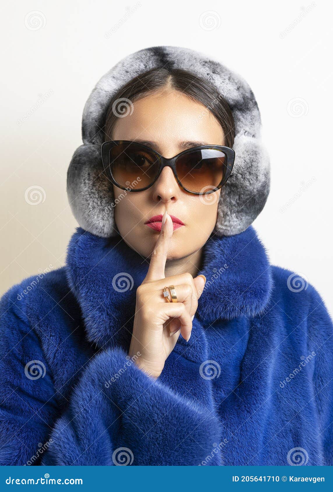 Orejeras de piel de invierno en mujer en abrigo de piel azul