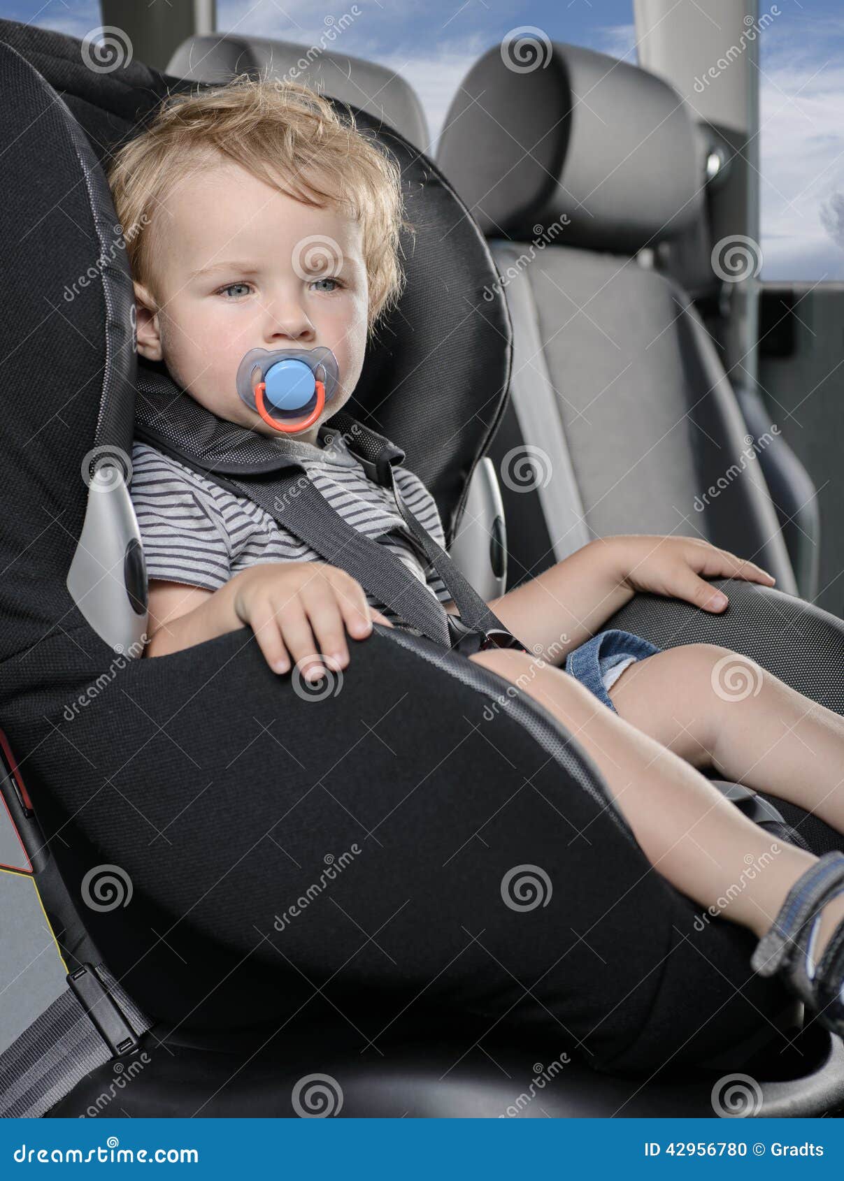 Auf weißem Hintergrund. Kind, das in einem Autobabykindersitz sitzt