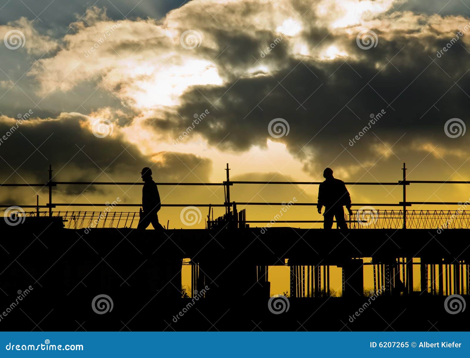 Aufbauleuteschattenbild. Schattenbild der Bauarbeiter auf Baustelle mit drastischem cloudscape.