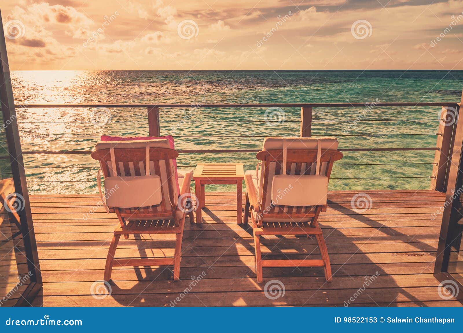 Aufpassender Sonnenuntergang in Malediven. Zwei Klappstühle auf einem Meer sehen Balkon an einem tropischen Erholungsort während des Sonnenuntergangs in Malediven an