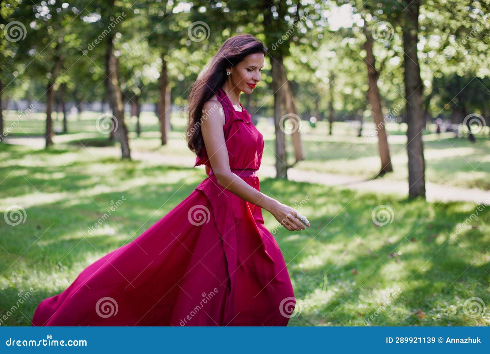 Authentic Portrait Of Beautiful Woman With Long Dark Hair Wearing Red Dress And Running In Park