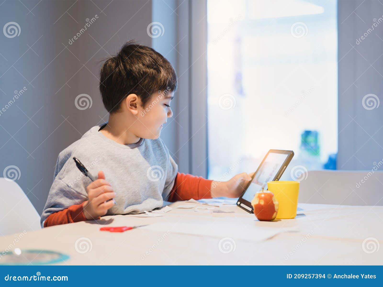 authentic portrait of preschool kid using tablet for his homework, new normal life child boy use touch pad for home learning, e-