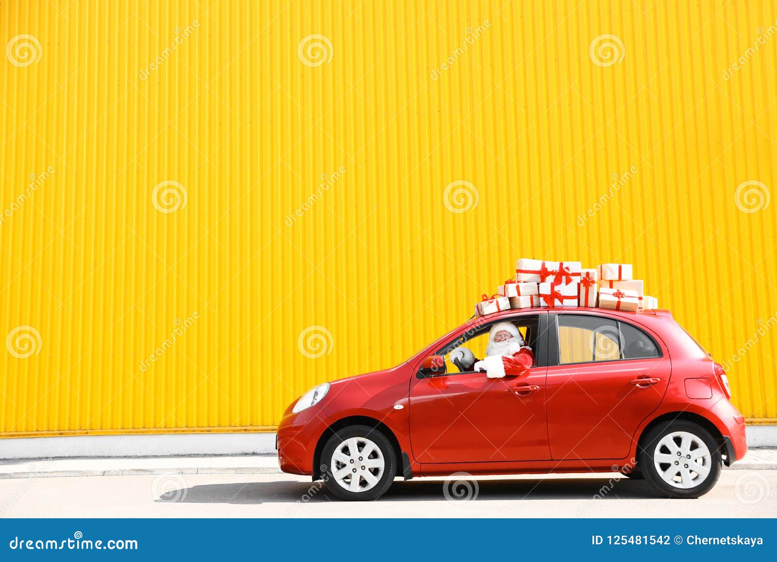 authentic santa claus driving red car with gift boxes