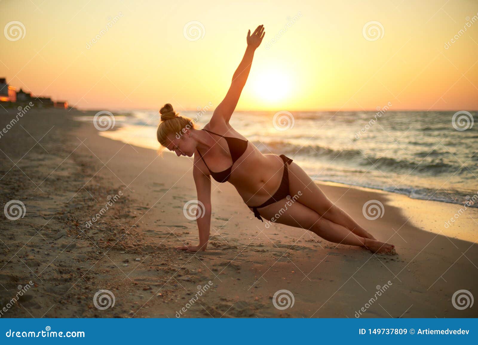 authentic woman in swimsuit doing yoga vasisthasana on the beach in the morning. real unretouched  girl silhouette