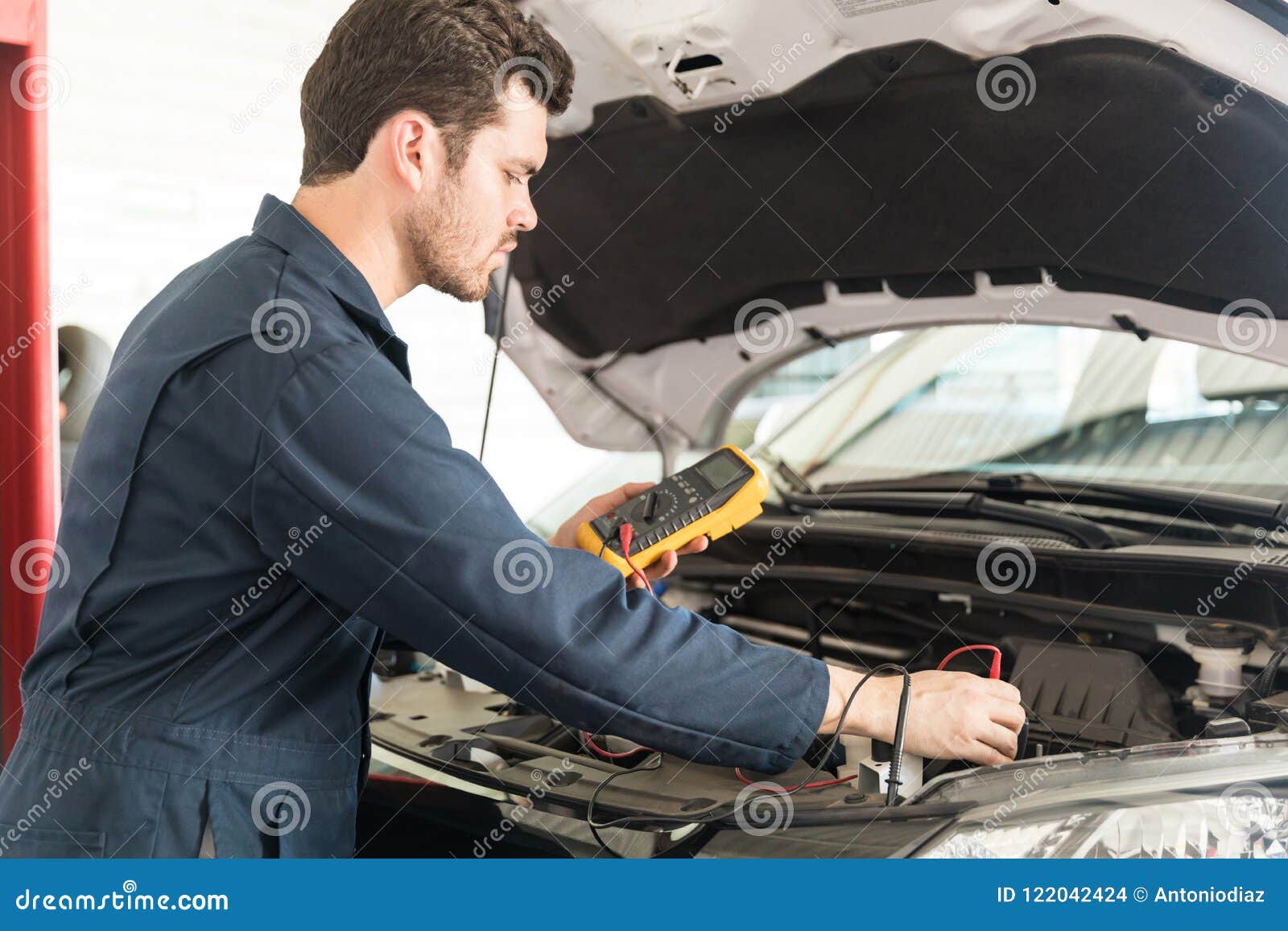 Auto Mechanic with Digital Multimeter Testing Car Battery Stock Photo