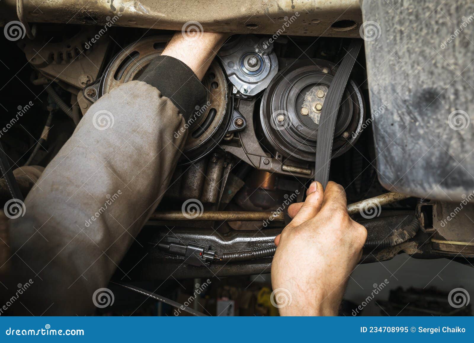 An Auto Mechanic Installs a Alternator Belt in a Passenger Car Engine