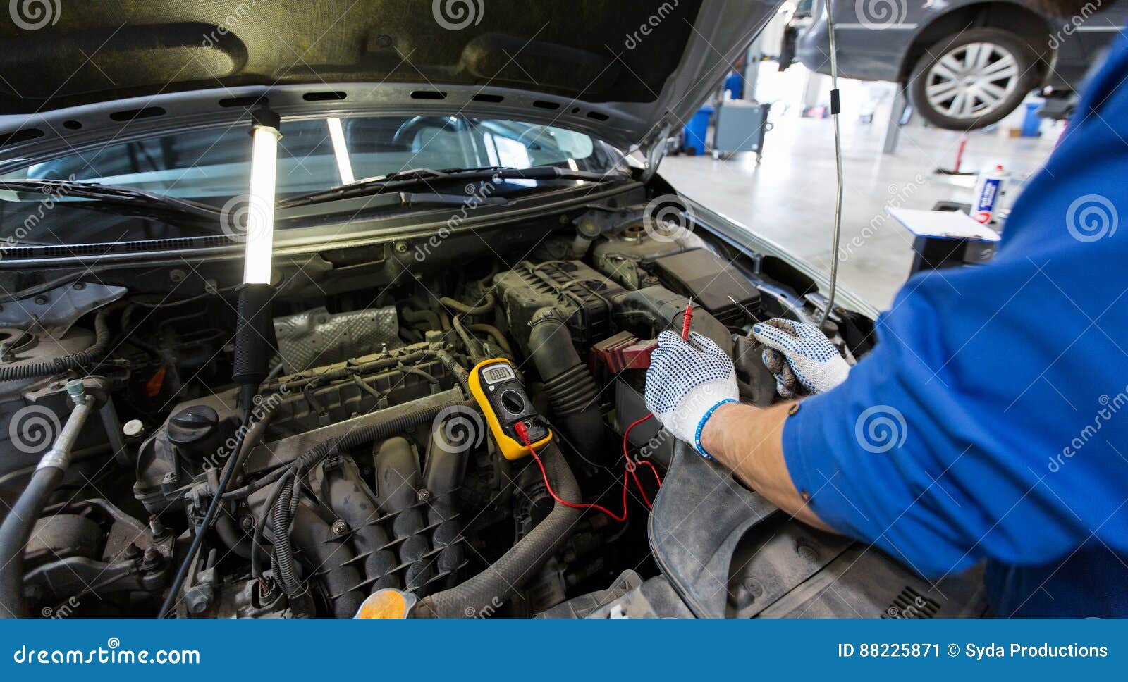 auto mechanic man with multimeter testing battery