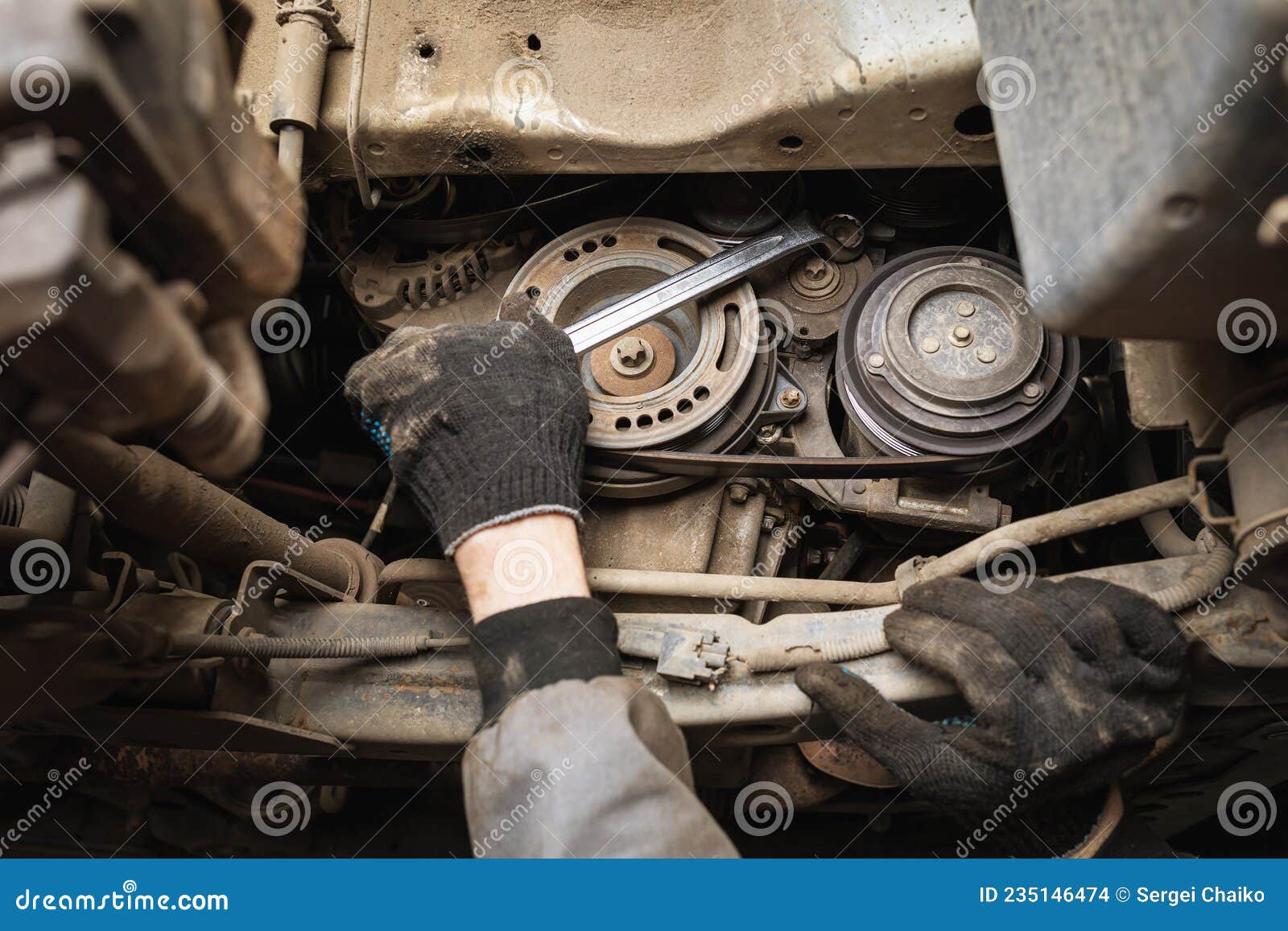 An Auto Mechanic Removes the Old Water Pump of a Car Engine Stock Photo