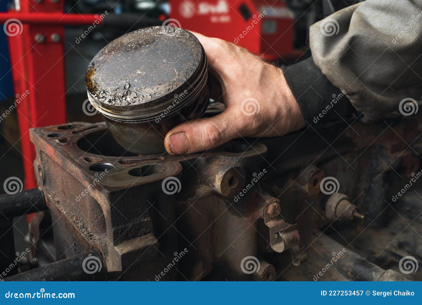An Auto Mechanic Shows a Worn Out Engine Piston with a Deformation on