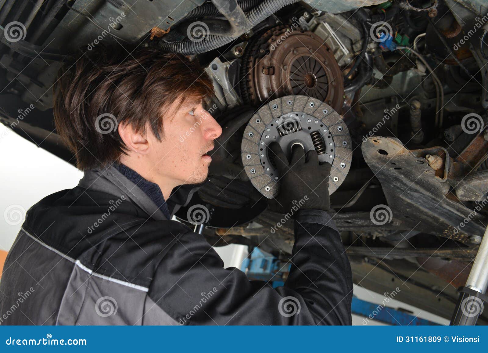 auto mechanic working under the car and changing clutch