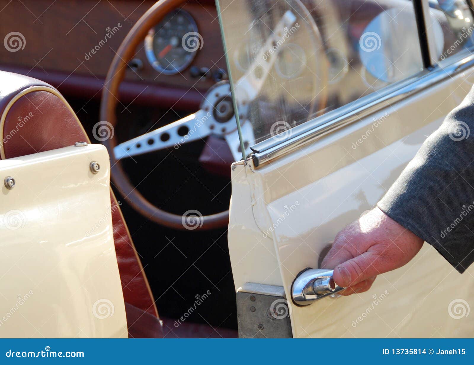 Automobile dell'annata con il chaufeur. Il Chauffeur tiene la maniglia di portello dell'automobile sull'automobile dell'annata