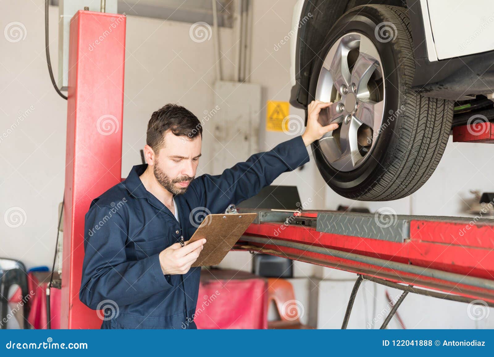 Automobile Engineer Examining Car Tire while Going through Check Stock