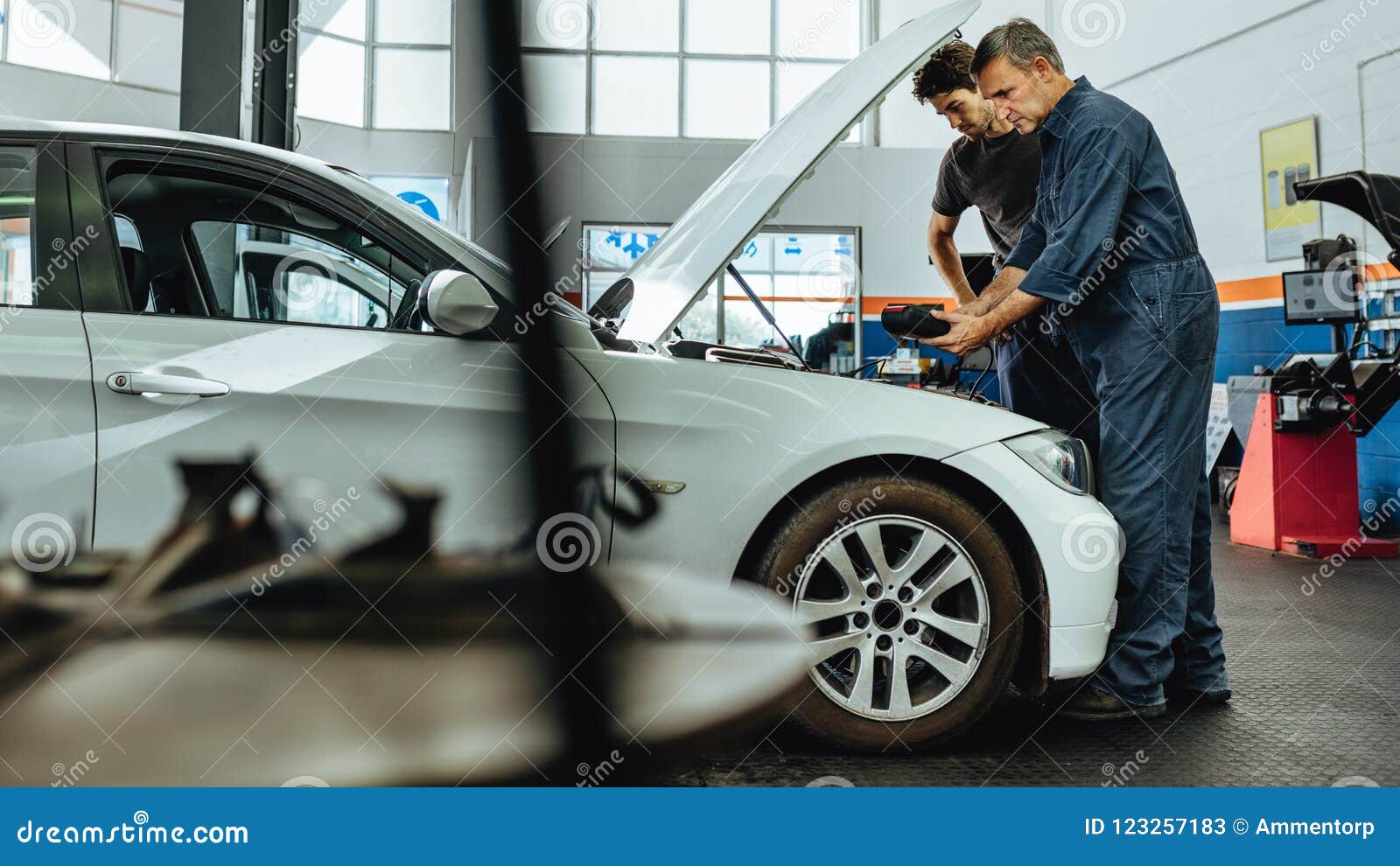 Mechanics Inspecting a Car Using an Electronic Device Stock Image