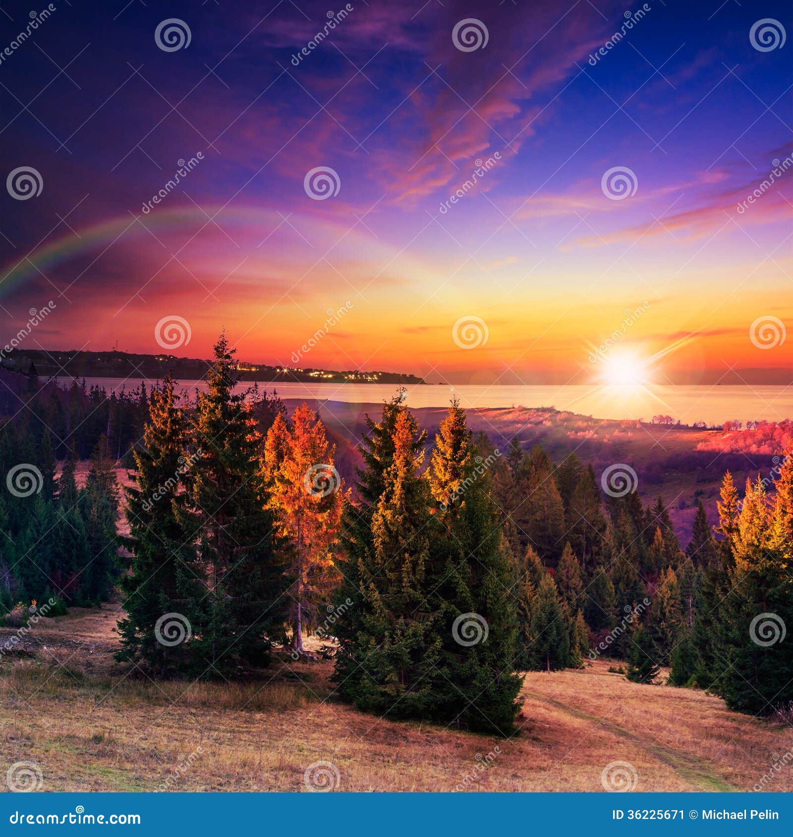 Autumn hillside with red and forest near the sea. Autumn landscape. forest on a hillside covered with red and yellow leaves. over the mountains against blue evening sky clouds