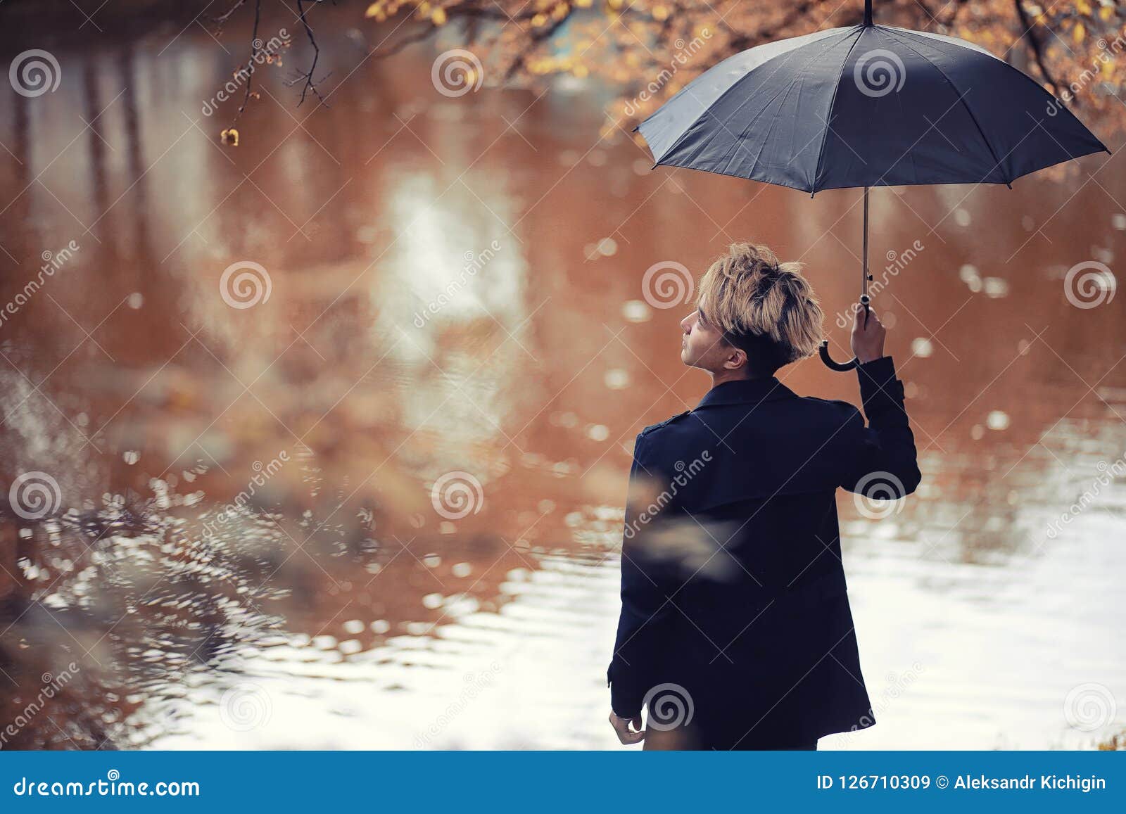 autumn rainy weather and a young man with an umbrella