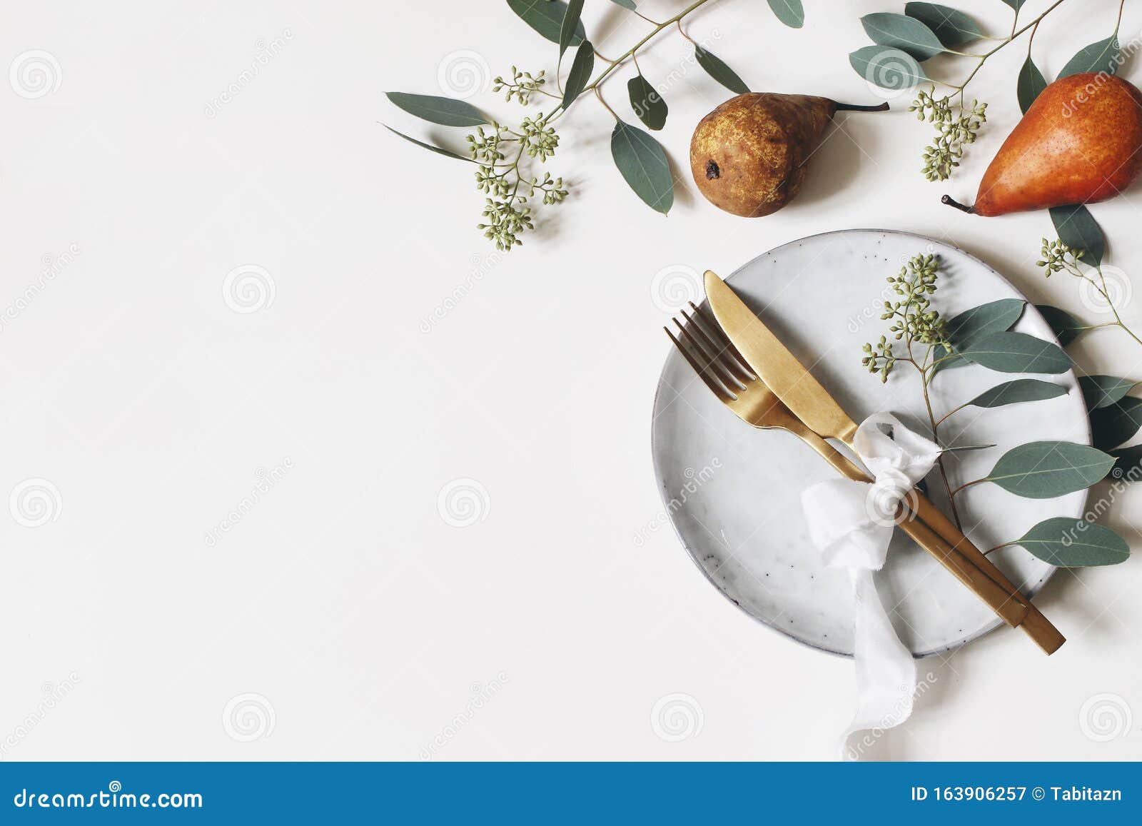 autumn thanksgiving table place setting. golden cutlery, porcelain plate, berry eucalyptus leaves and branches, silk