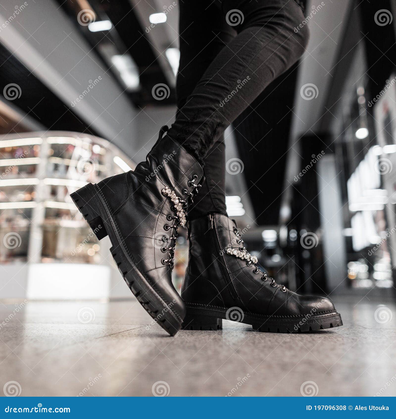 Close Up Of Female Legs In Black Trendy Jeans In Leather Black Stylish Boots  With Red Soles. Fashionable Woman Is Standing On A Tile Indoors. Retro  Style. Autumn Fashion Women's Shoes. Stock