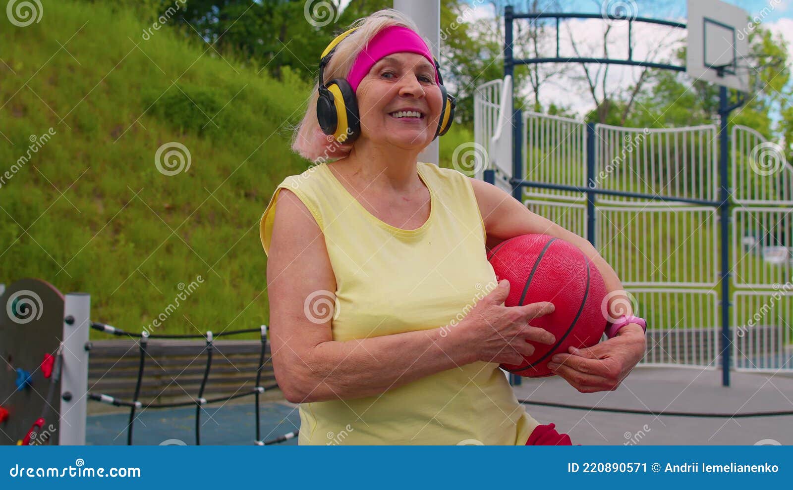 Esportivo com bola para jogar basquete, ouvindo música em fones de ouvido  no parquinho do campo