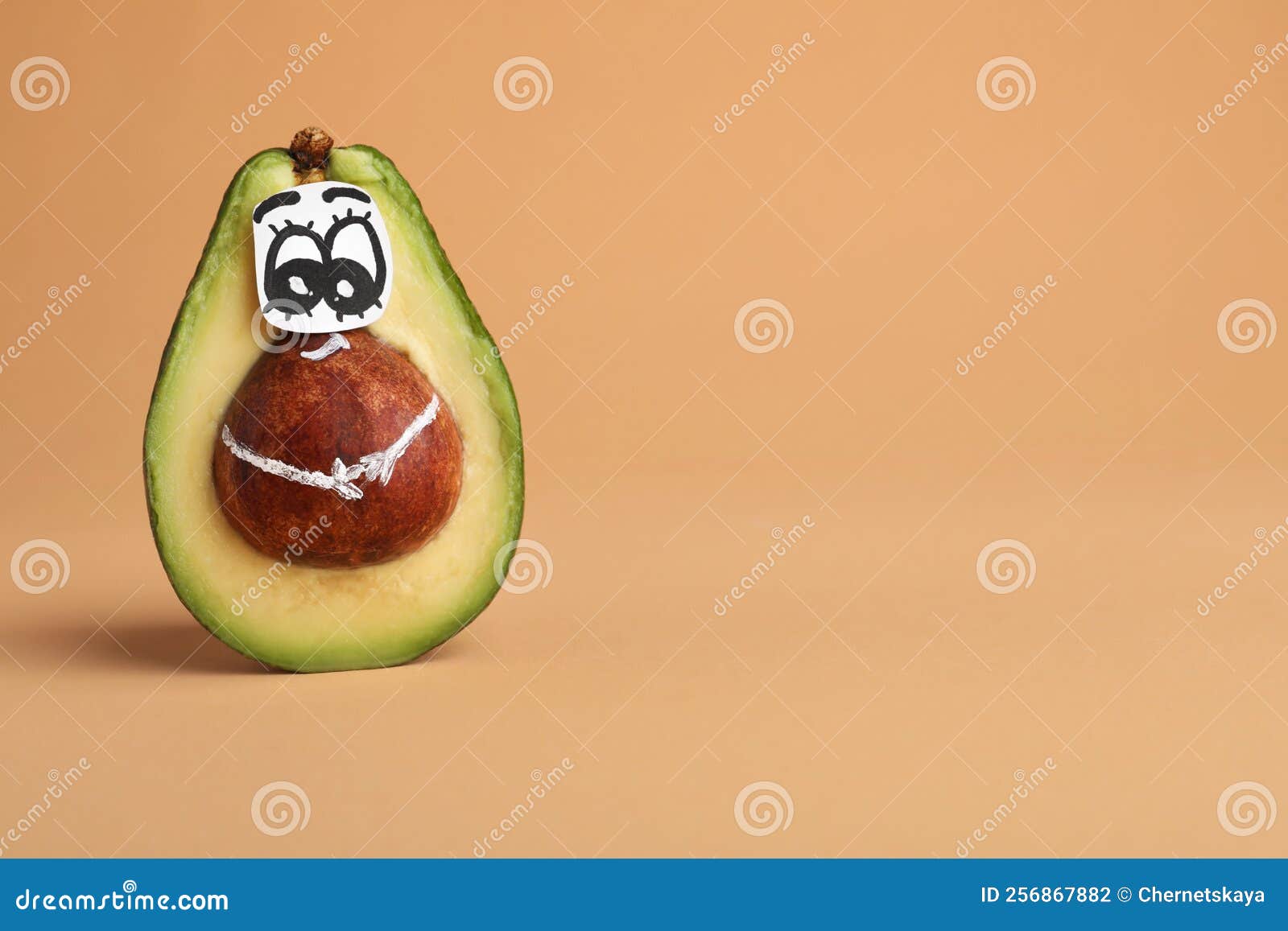 Avocado with Drawn Face on Orange Background, Space for Text