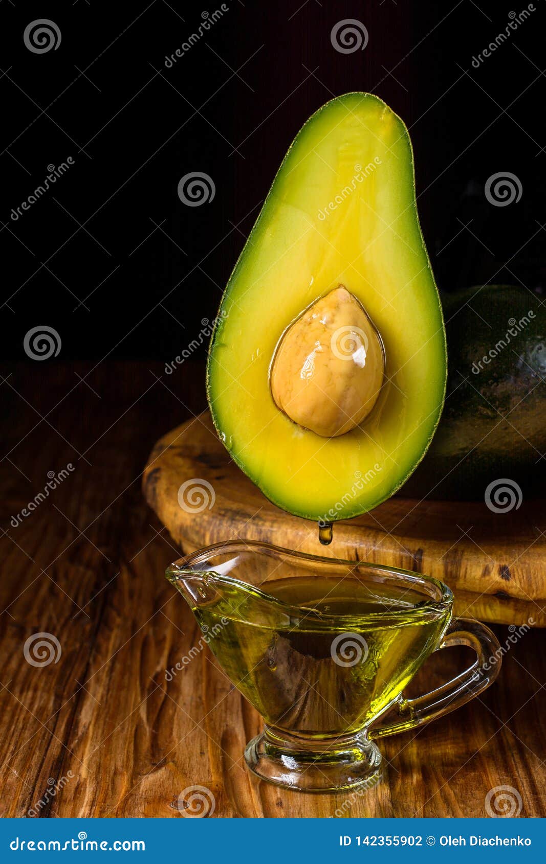 Avocado Oil Drops Drain Into A Glass Bowl. Avocado Fruit 