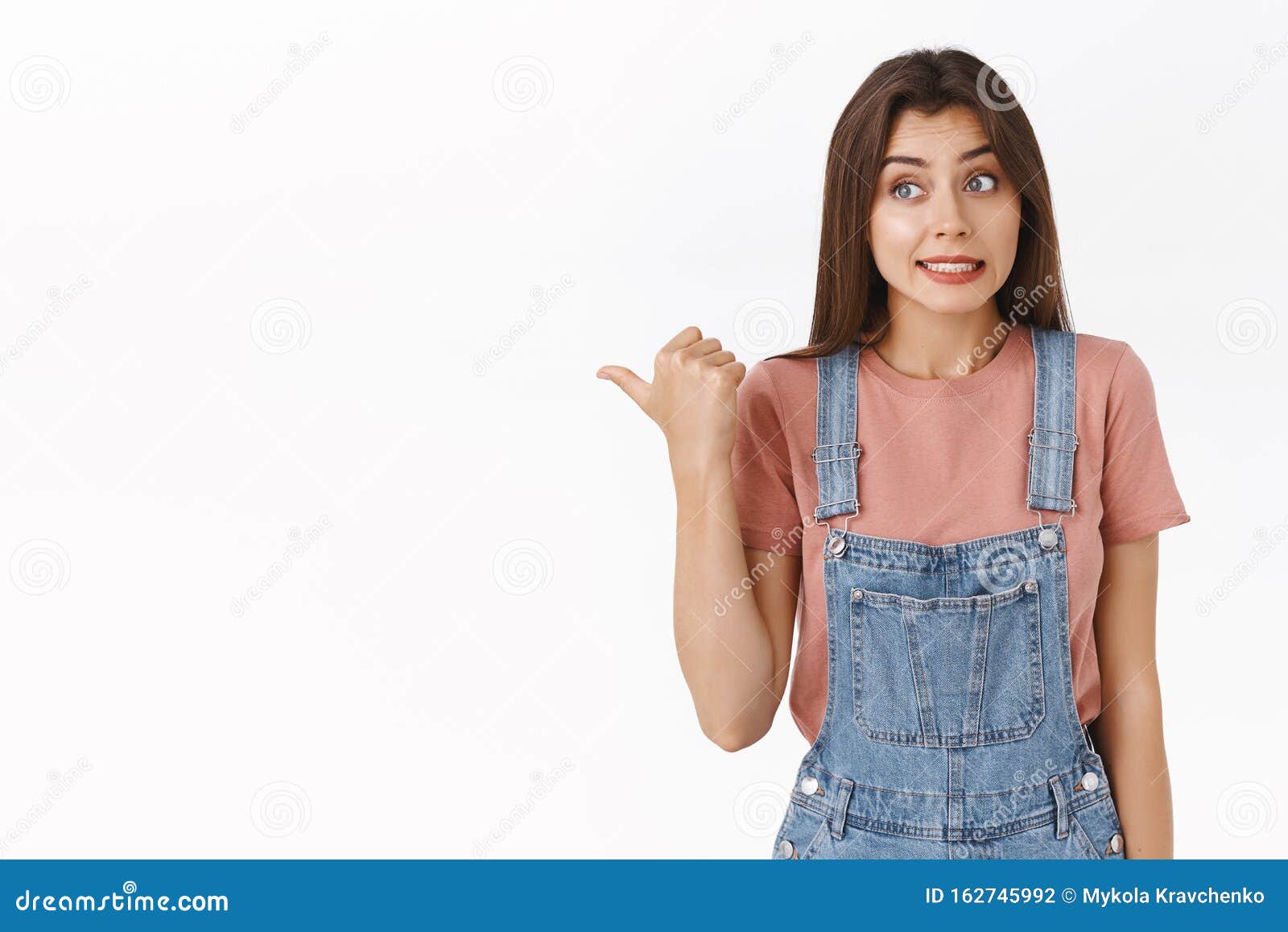 Awkward And Slightly Worried Cute Brunette Female In Overalls T Shirt