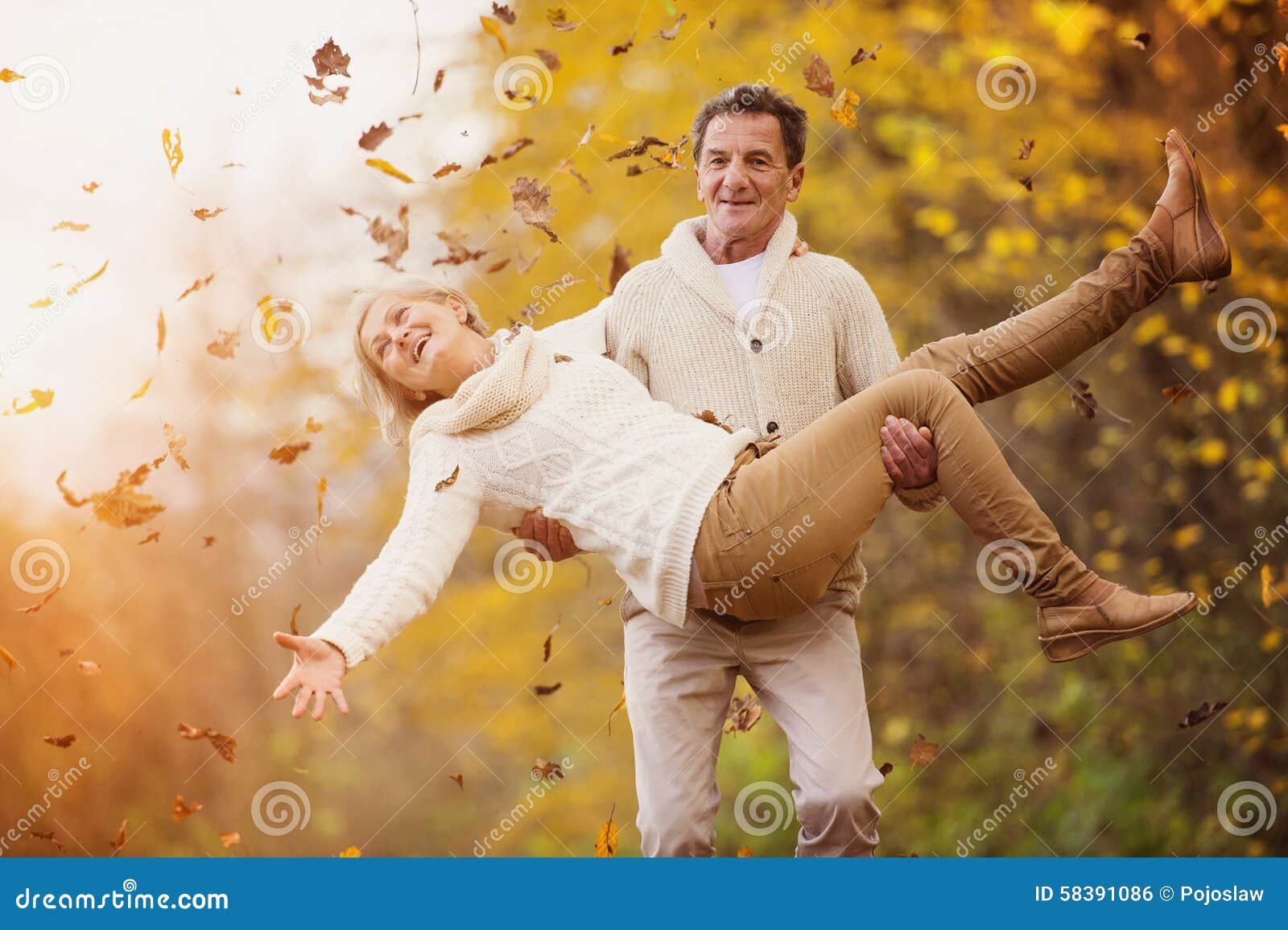 Aînés actifs ayant l'amusement en nature. Aînés actifs ayant l'amusement et jouant avec les feuilles dans la forêt d'automne