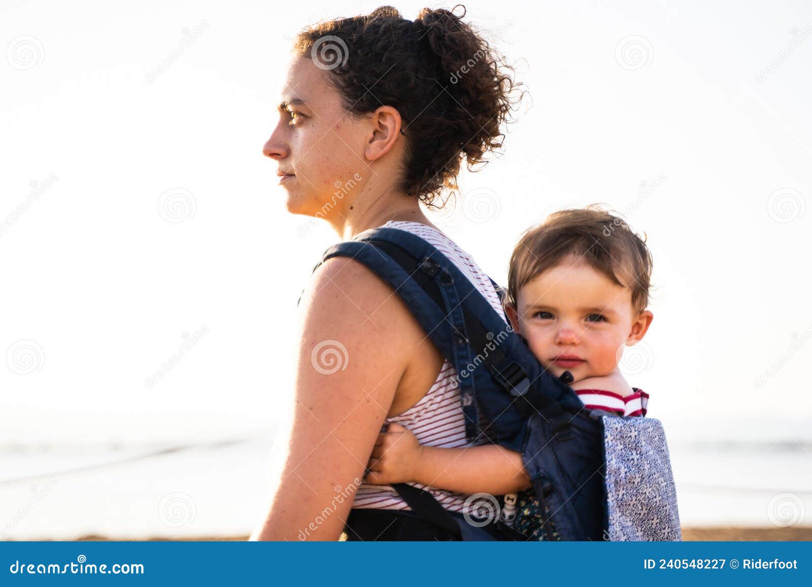 Bébé Regardant La Caméra Pendant Qu'elle Est Suspendue à L'arrière De Sa  Mère Image stock - Image du inclus, childcare: 240548227