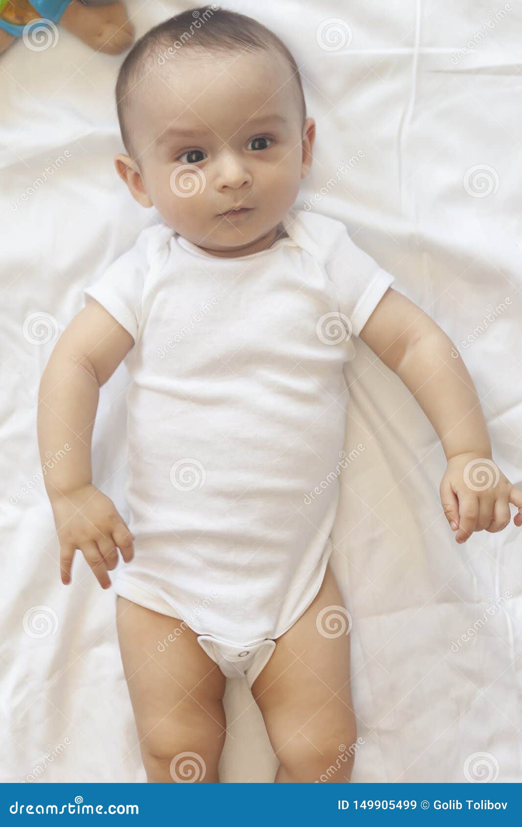 68monthold Baby Boy Lying Playfully in Bed. Charming 67 Month Little Baby in White Bodysuit