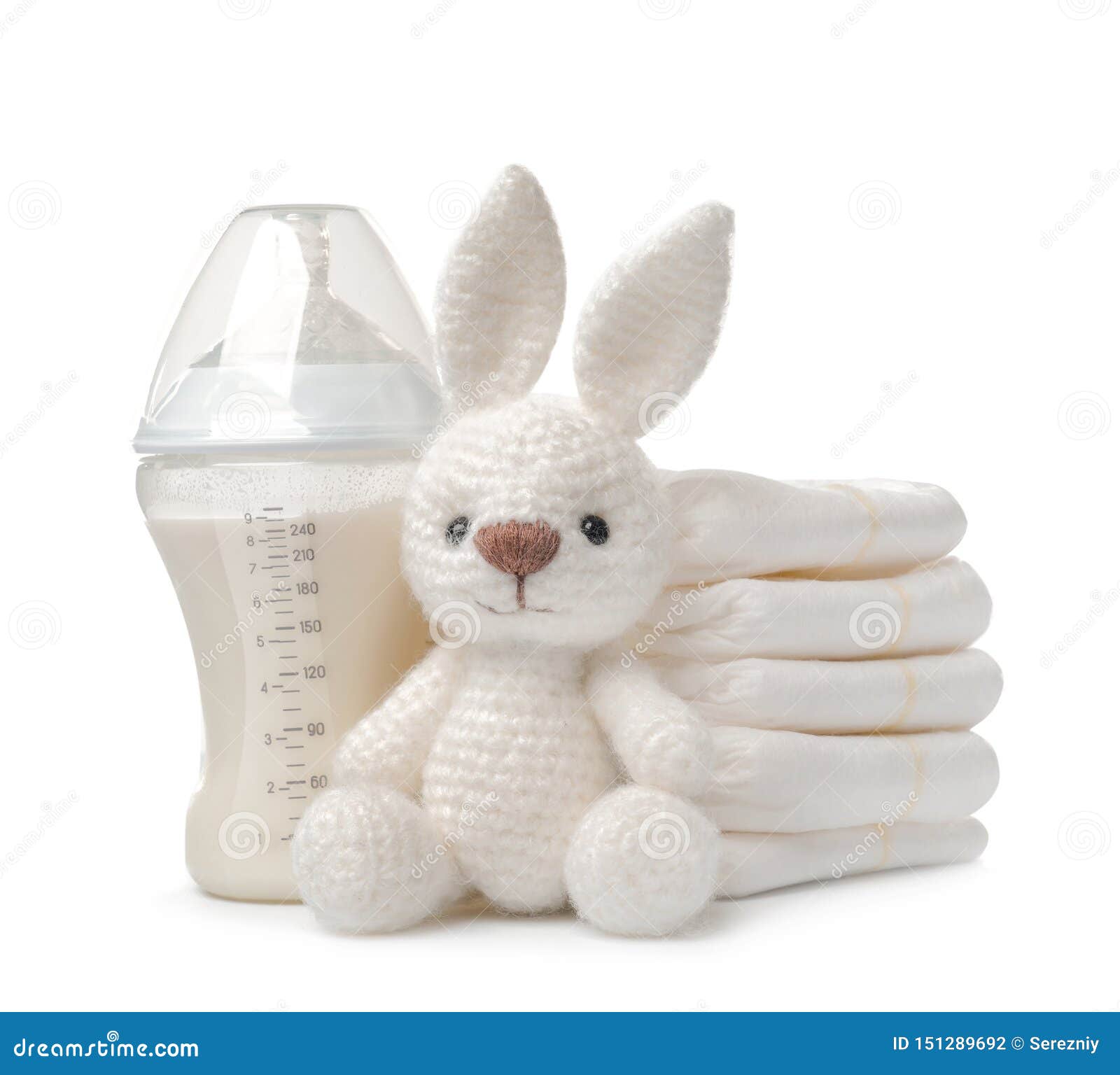 Baby Bottle with Milk, Bunny Toy and Stack of Diapers on White