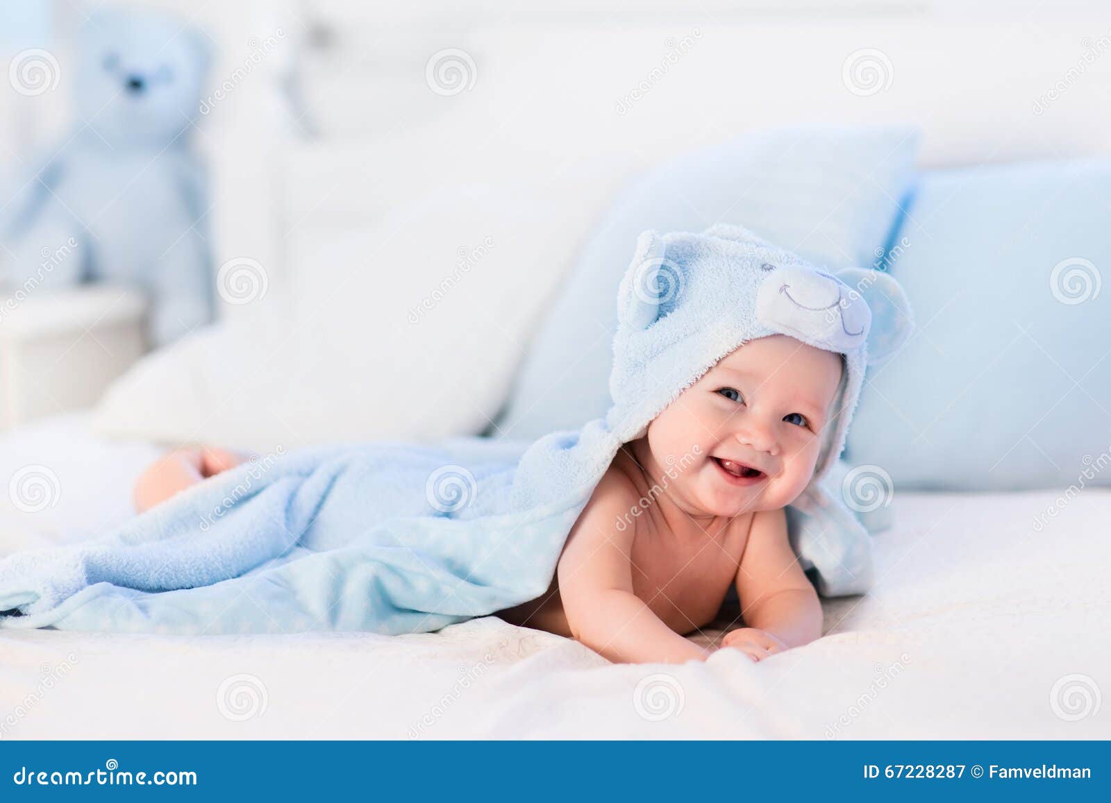 baby boy in blue towel on white bed