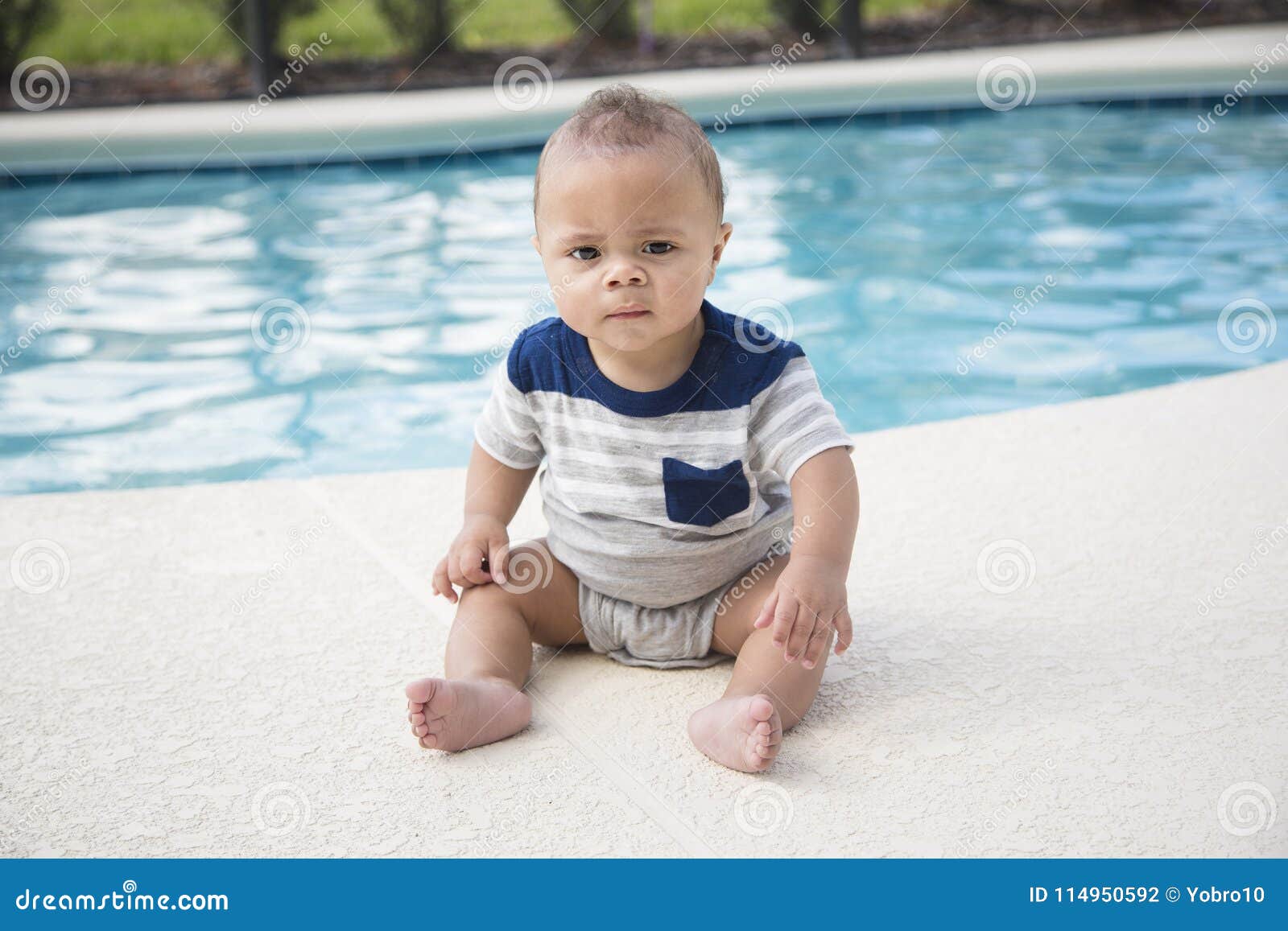 baby boy sitting dangerously on the edge of a swimming pool
