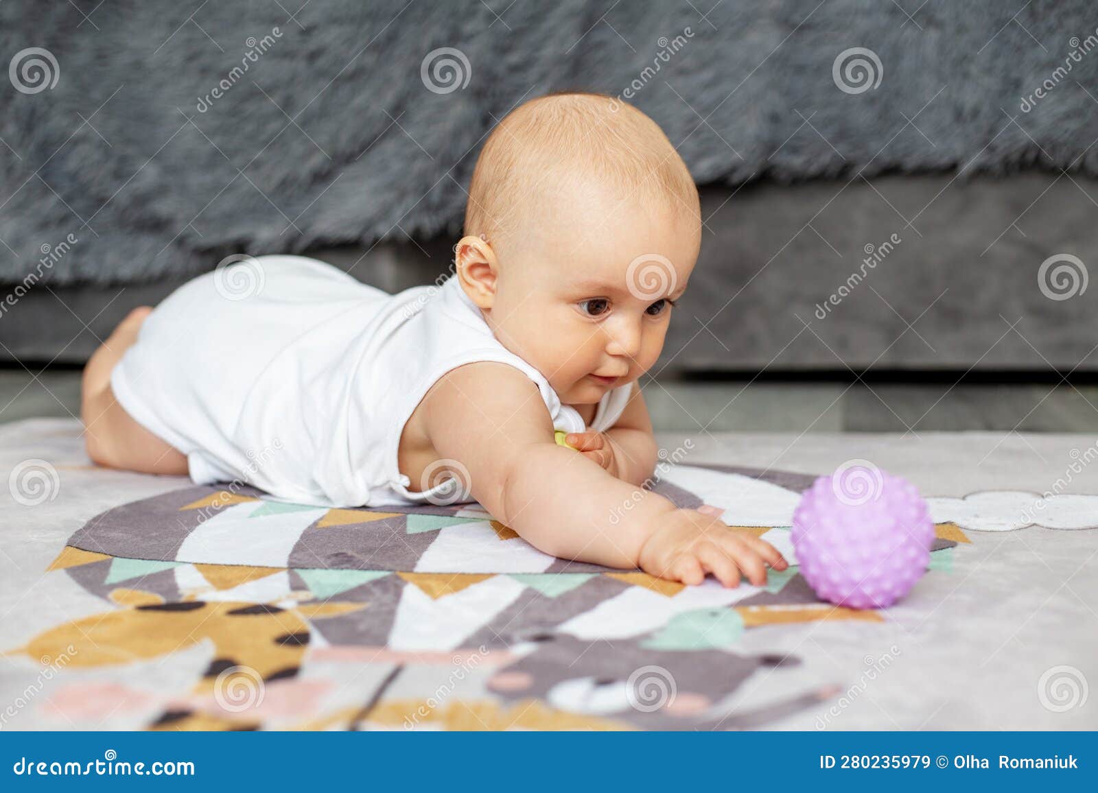 baby creep on floor of nursery grabbing colorful ball. baby development. sensory experience