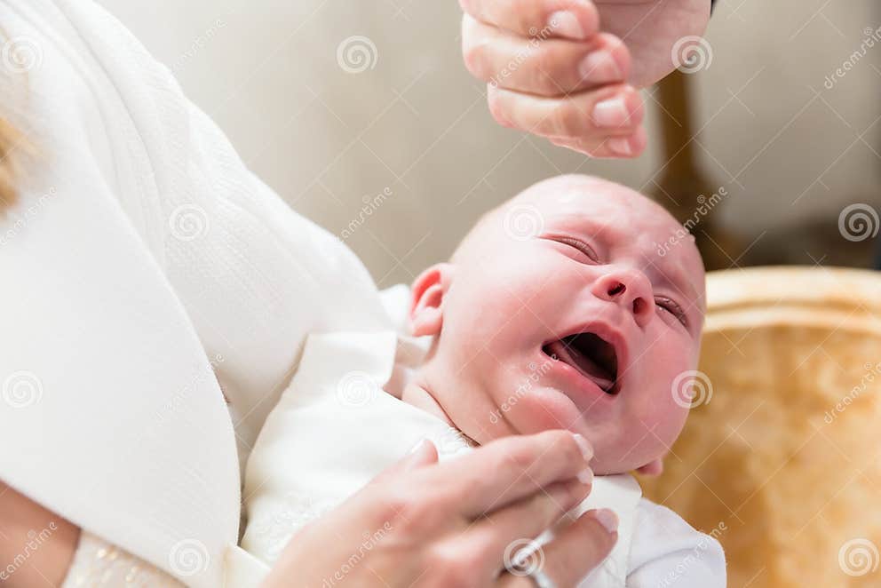 Baby is Crying at Christening while the Priest Pours Holy Water Stock