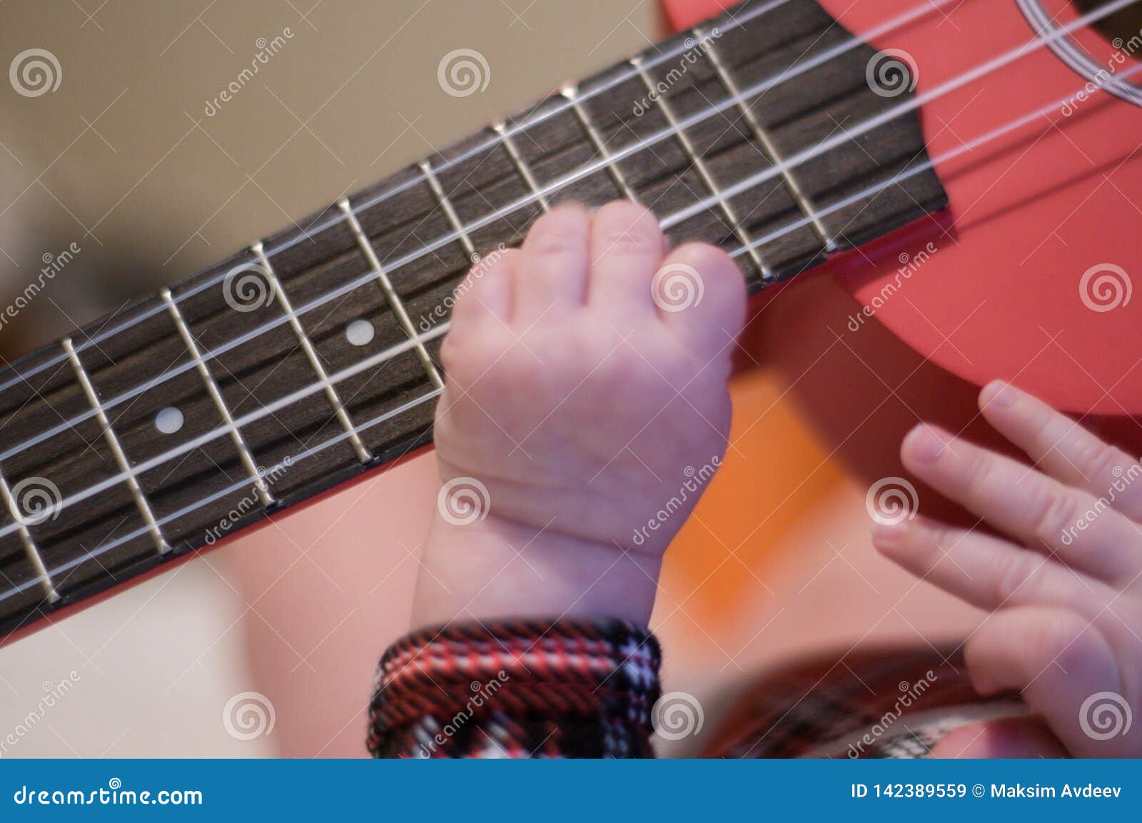 Baby Fingers Plays Guitar. Ukulele Strings and Frets Stock Image