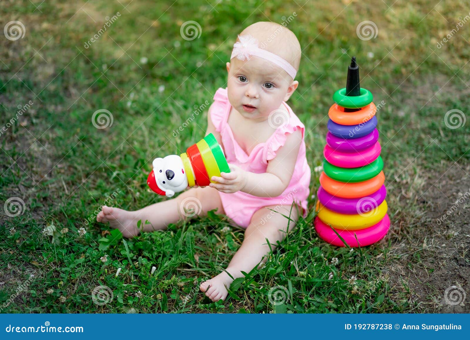 baby girl 10 months old sitting on the grass in the summer and playing pyramid, early development of children, outdoor games