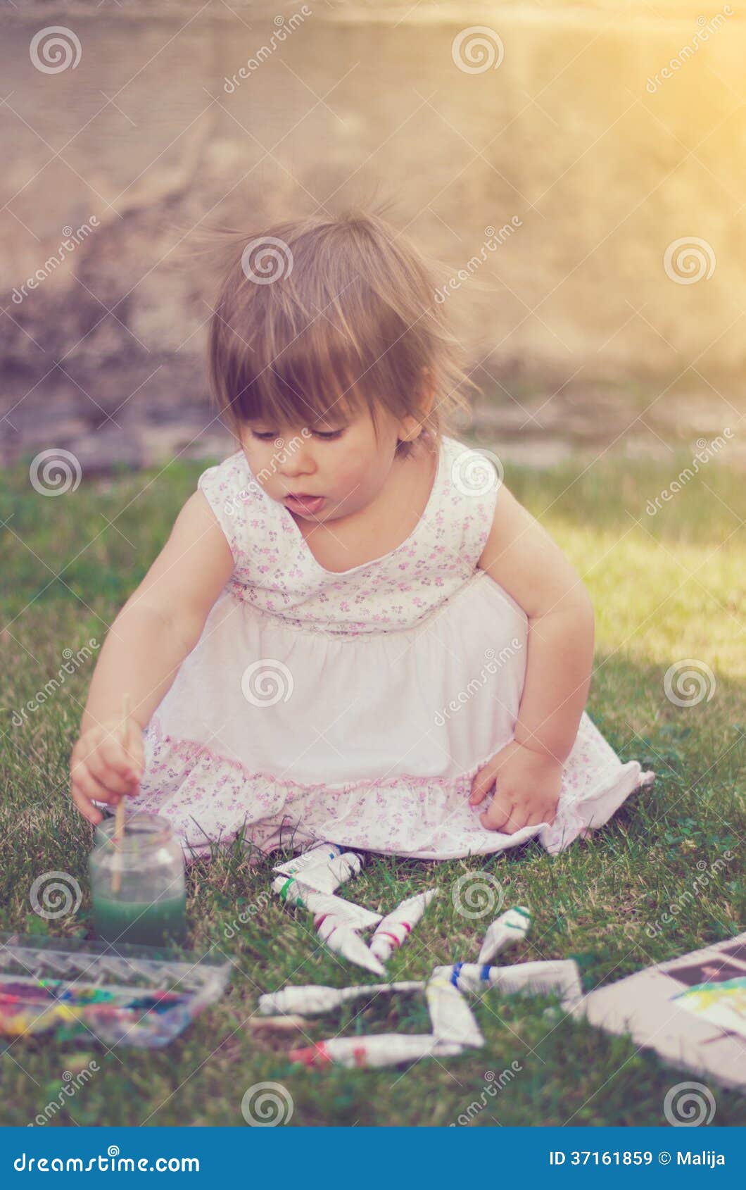 Little baby girl painting in yard