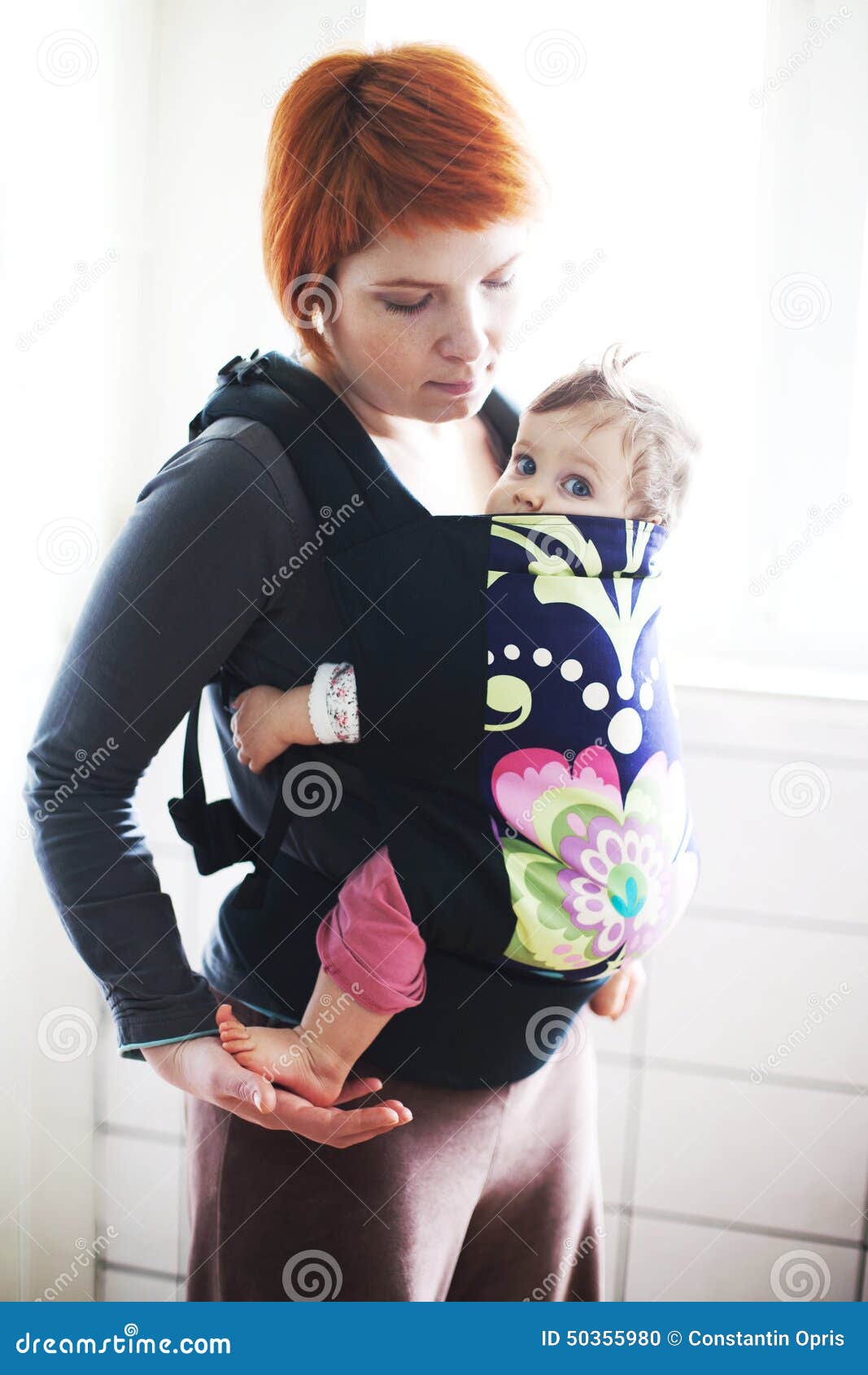 baby held by his mother in a baby carrier